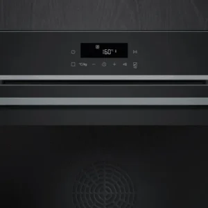 Le four SIEMENS HB472G0B3, doté d'un affichage numérique réglé sur 160°C, est parfaitement intégré dans un fond de panneaux en bois foncé pour un look épuré.