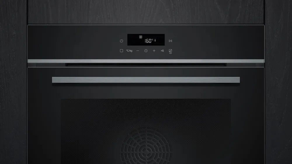 Le four SIEMENS HB472G0B3, doté d'un affichage numérique réglé sur 160°C, est parfaitement intégré dans un fond de panneaux en bois foncé pour un look épuré.