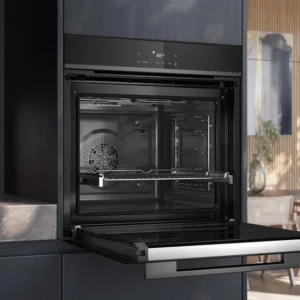 Le four encastrable SIEMENS HB472G0B3 se dresse avec sa porte ouverte dans une cuisine élégante rehaussée par d'élégantes touches de bois et de marbre.