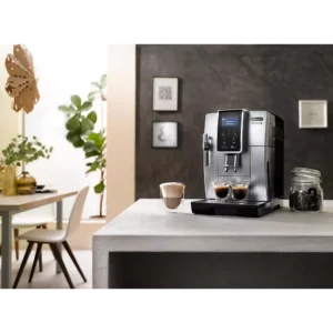 Une machine à espresso DELONGHI FEB3535.SB est posée sur le comptoir de la cuisine avec des tasses à café, un pot de grains et un décor moderne et élégant en arrière-plan.