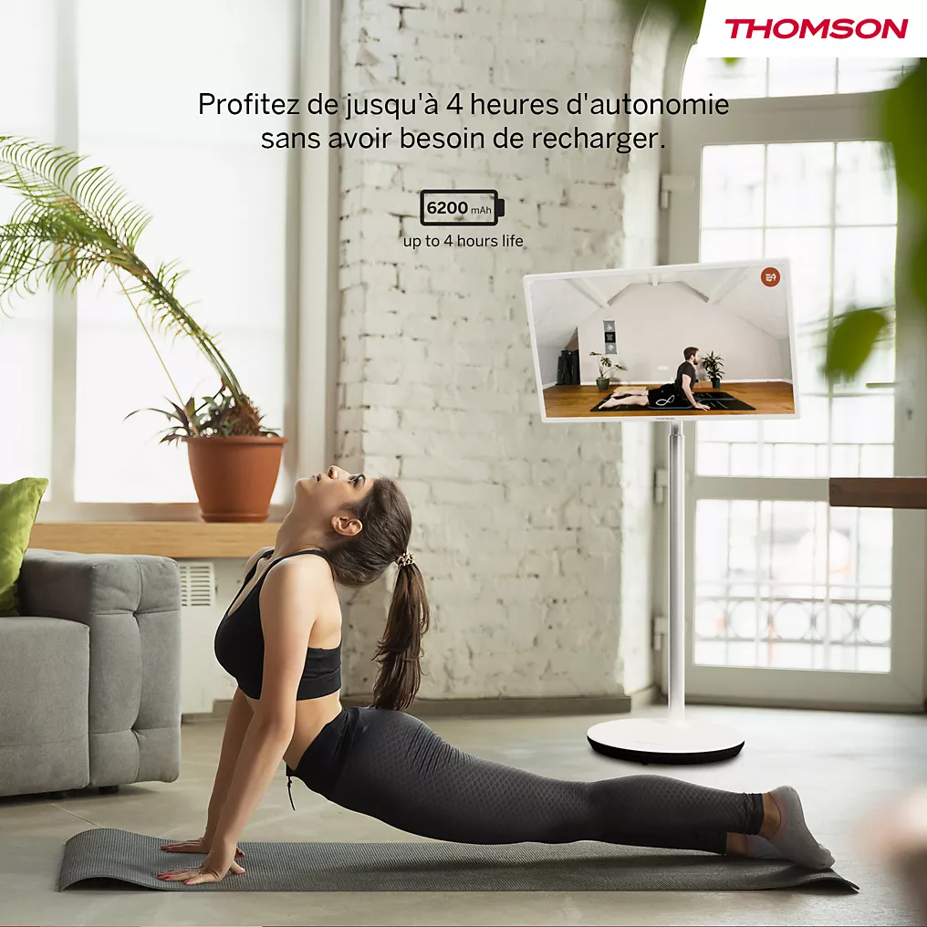 Une femme pratique le yoga en intérieur, en suivant un cours en ligne sur un téléviseur THOMSON 32HA4M44, le logo Thomson étant visible sur l'écran.
