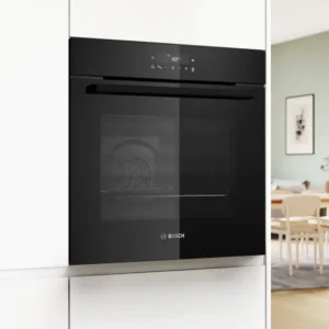 Le four BOSCH HBA4720B3F (Copie), doté d'une élégante porte en verre noir, s'intègre parfaitement dans une cuisine blanche moderne et lumineuse, à proximité d'une salle à manger éclairée par le soleil.