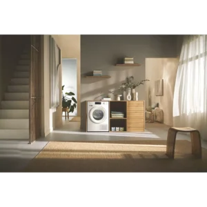 Buanderie moderne avec un sèche-linge MIELE TSC643WP, une machine à laver, des armoires en bois, des étagères, des plantes et beaucoup de lumière naturelle.