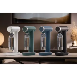 Quatre machines à soda SMEG, dont la SKC01BLM NOIR MAT, ainsi que des modèles en blanc, vert et bleu, sont exposées ensemble à l'intérieur.