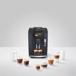 La machine à café JURA E8 COSMIC BLACK (ED) est entourée de huit verres remplis de différentes boissons au café, d'eau et de lait sur une surface blanche.