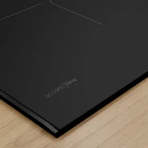 Gros plan sur une plaque de cuisson à induction BOSCH PVW89BHC1E noire et élégante, portant l'étiquette "accent | line", posée sur un plan de travail en bois clair.