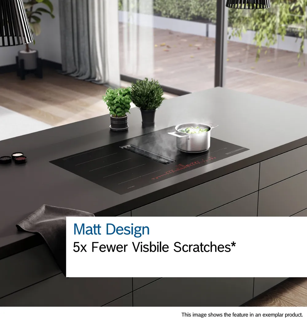 Cuisine moderne équipée de la table de cuisson BOSCH PVW89BHC1E noir mat ; casserole fumante et herbes fraîches sur le comptoir. La résistance aux rayures est soulignée dans le texte.