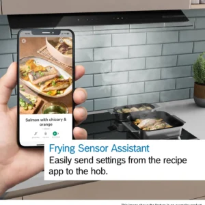 Une main tient un téléphone avec une recette de saumon devant la table de cuisson BOSCH PVW89BHC1E, où le saumon grésille dans une poêle.
