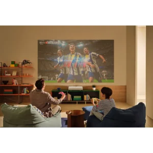 Deux personnes regardent un match de football sur un grand écran projeté par le SAMSUNG SP-PLU7D dans un salon moderne et élégant.