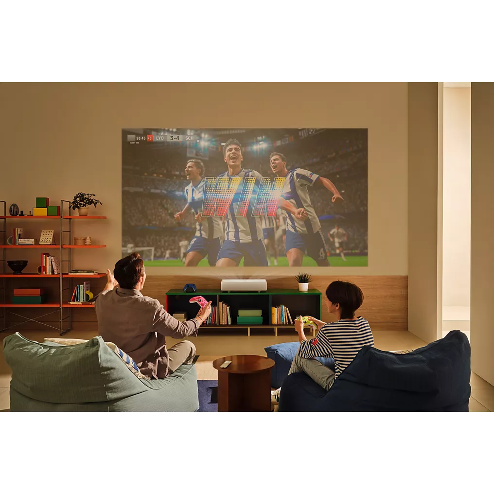 Deux personnes regardent un match de football sur un grand écran projeté par le SAMSUNG SP-PLU7D dans un salon moderne et élégant.