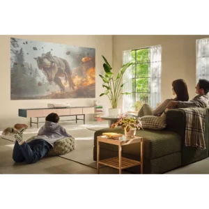 Une famille regarde un film d'action sur les dinosaures sur un grand écran dans leur salon moderne et lumineux, projeté par le SAMSUNG SP-PLU7D.