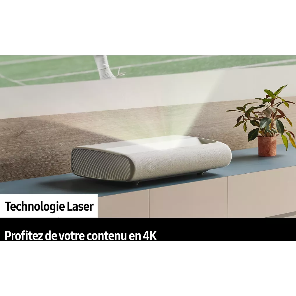 Le projecteur laser SAMSUNG SP-PLU7D projette des images nettes sur le mur d'un salon moderne avec une plante à proximité, ce qui confère à l'espace une ambiance élégante et raffinée.
