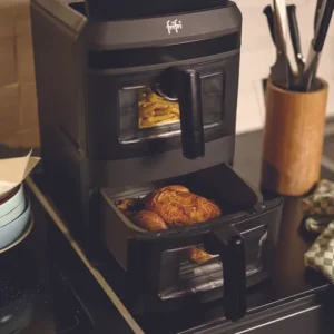 Le FRIFRI AIRFRYER DUO SLIM est posé sur le comptoir de la cuisine. Il fait cuire des frites dans le tiroir supérieur et du poulet dans le tiroir inférieur.