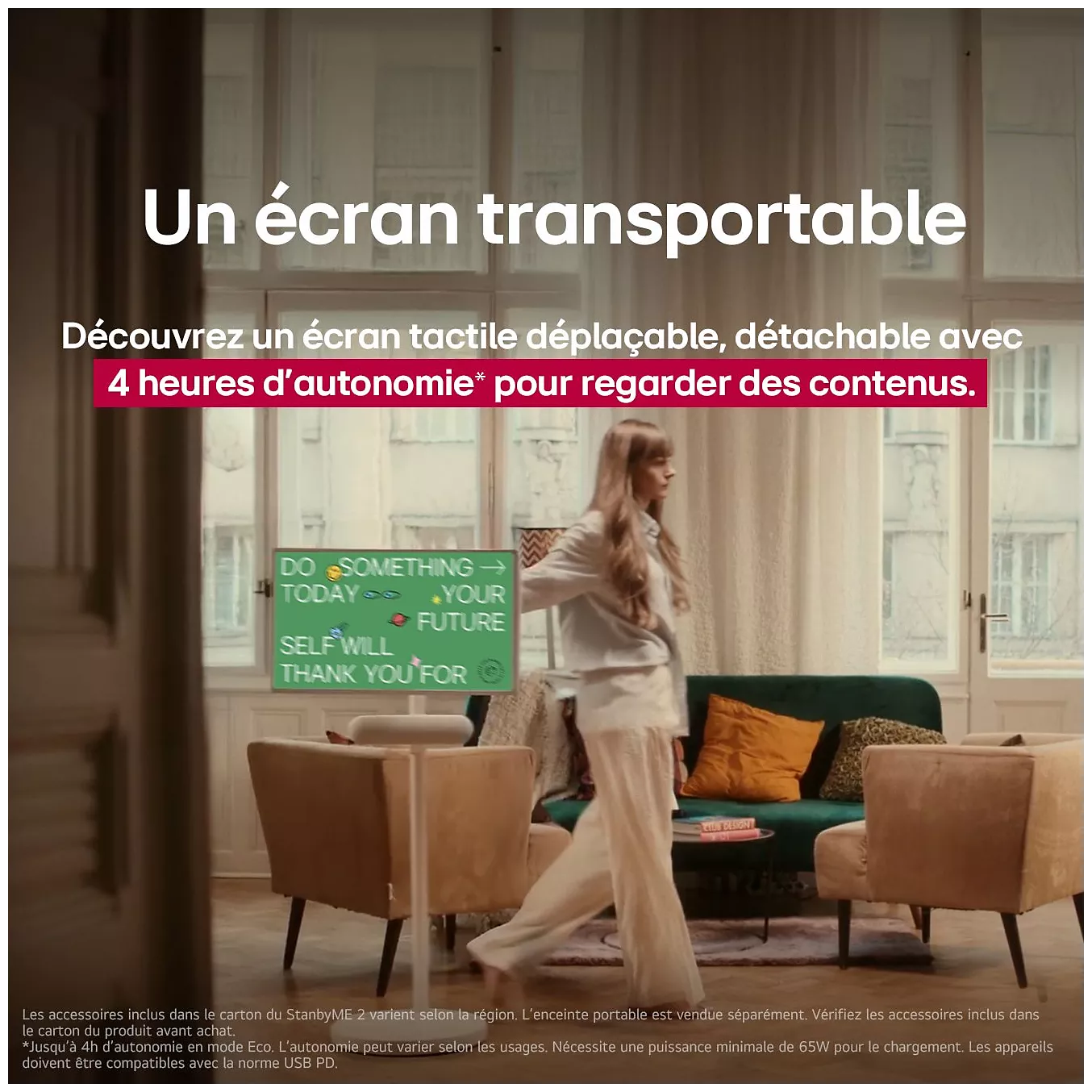 Une femme se tient dans un salon près du LG 27LX6 STANDBYME, qui affiche un texte de motivation, avec un canapé et une table à proximité.