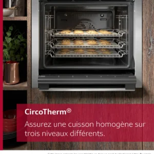 Le four NEFF B2ACJ7AG0, avec trois plateaux de biscuits cuisant uniformément à l'intérieur, est posé à côté d'une plante sur un comptoir en bois.