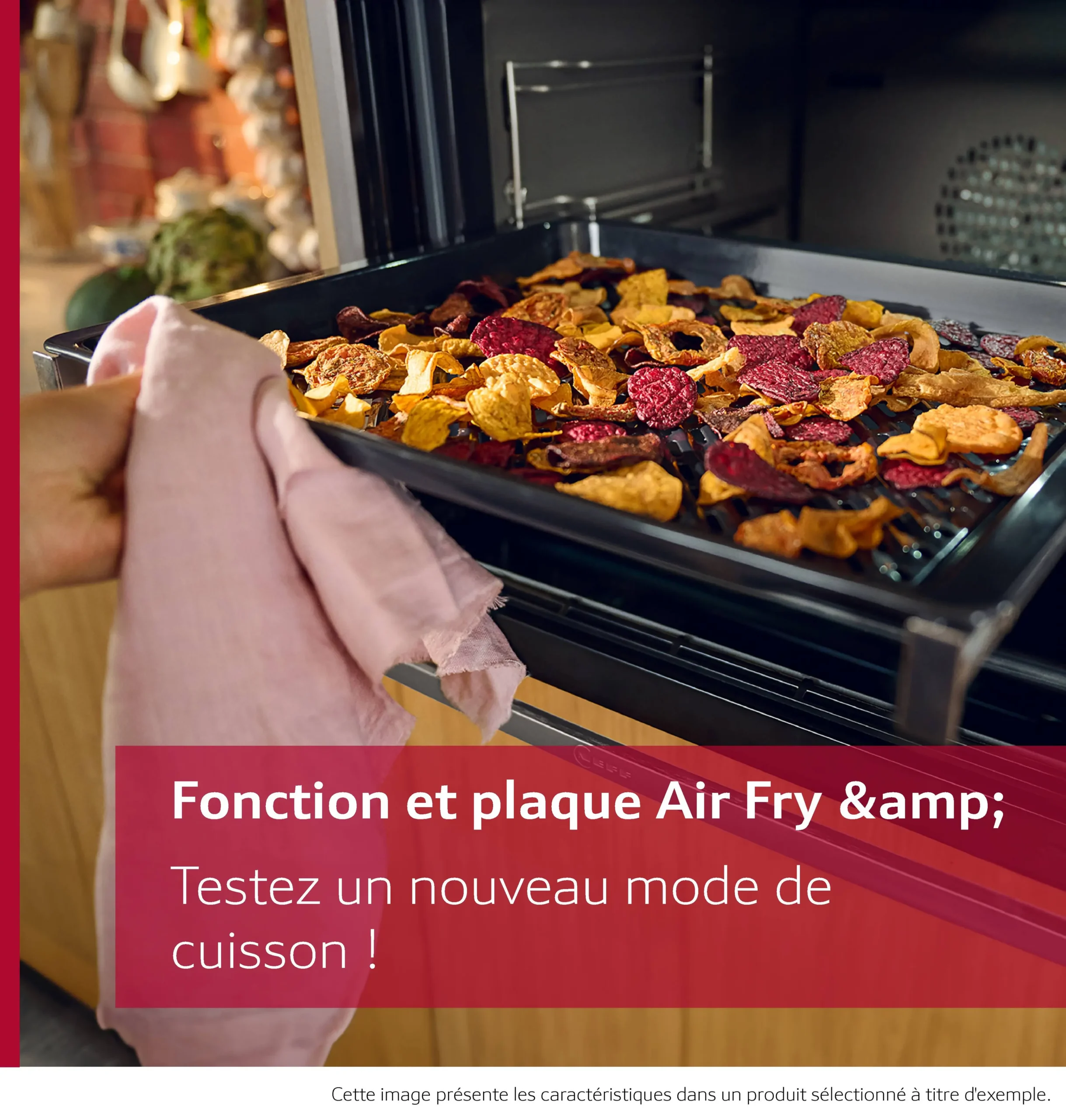 Une main utilise un chiffon pour glisser un plateau de légumes secs colorés dans le four NEFF B2ACJ7AG0, en sélectionnant le mode Air Fry.