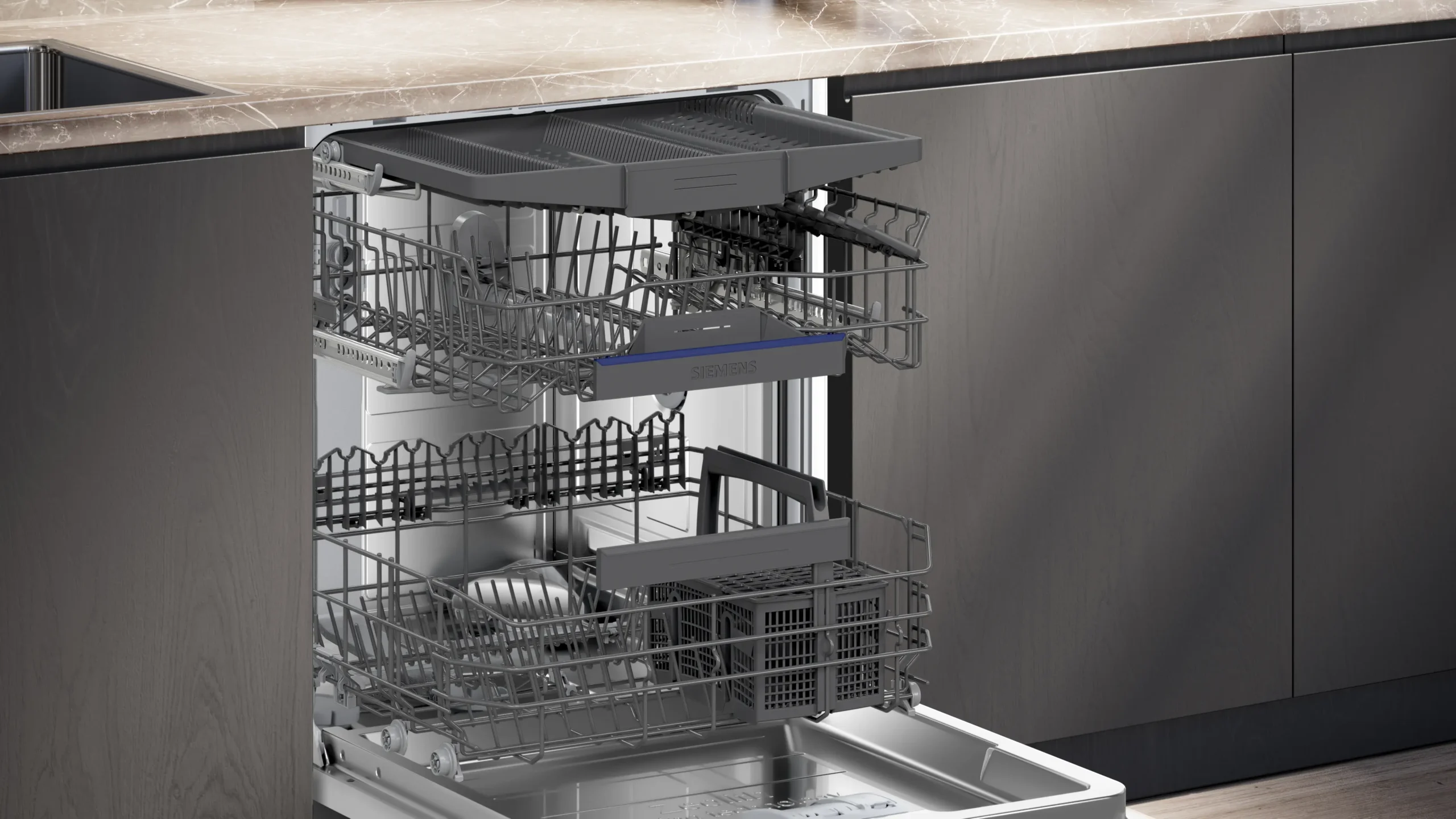 Ouvrez le lave-vaisselle moderne SIEMENS SN65Z804CE, équipé de trois paniers coulissants vides, situé sous un plan de travail en marbre dans une cuisine élégante.