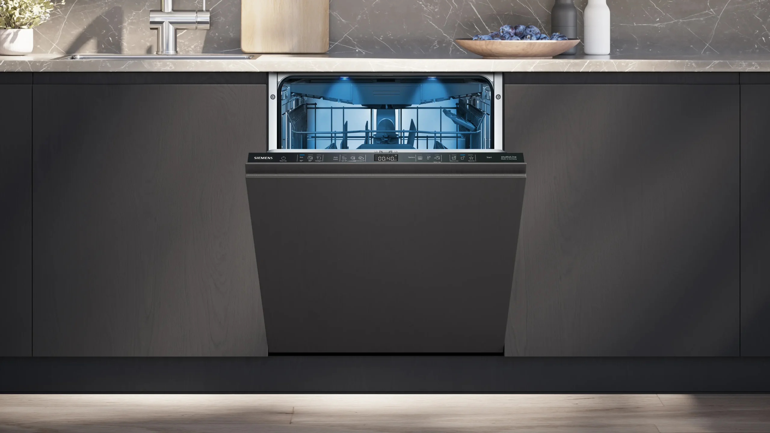 Le lave-vaisselle encastrable SIEMENS SN65Z804CE est présenté ici avec la porte ouverte, dévoilant ses paniers vides et éclairés par un éclairage intérieur bleu.
