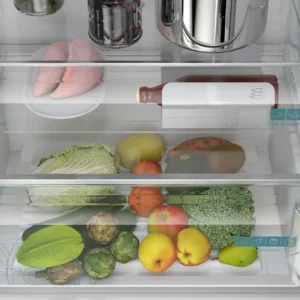 Ouvrez le tiroir du réfrigérateur SIEMENS KG49NEICU pour découvrir un assortiment de fruits et légumes, une bouteille et de la viande emballée sur l'étagère en verre située au-dessus.