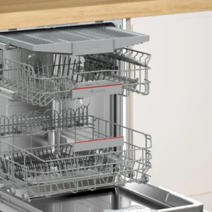 Dans une cuisine d'un blanc éclatant, le lave-vaisselle BOSCH SMI4HCB07E est posé proprement sous un plan de travail en bois, avec ses casiers vides ouverts.