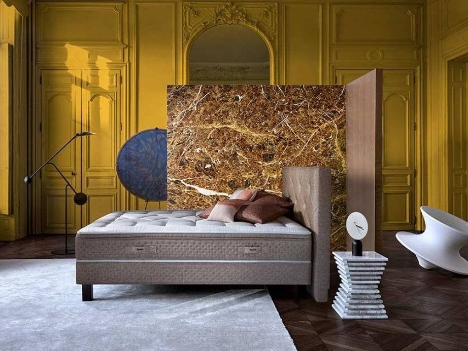Une chambre à coucher moderne avec un mur jaune orné, une cloison en marbre, un lit neutre équipé du matelas EPEDA GALACTIQUE 2 160x200 et un mobilier contemporain.
