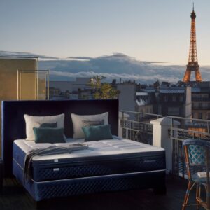 Un lit EPEDA PERSÉIDES 2 160x200 sur un balcon parisien au coucher du soleil avec la Tour Eiffel en arrière-plan.