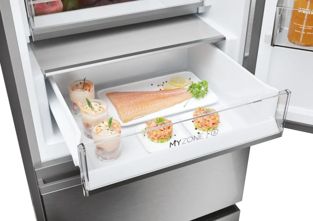 Le tiroir du réfrigérateur HAIER HTW5618ENMG présente des plateaux blancs "MYZONE" contenant du saumon, un cocktail de crevettes et des aliments garnis.