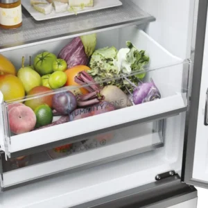 Ouvrez le tiroir du réfrigérateur HAIER HTW5618ENMG, rempli de fruits et de légumes frais tels que des pommes, de la laitue et des aubergines.