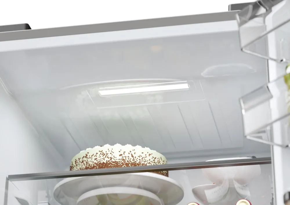 L'intérieur du réfrigérateur HAIER HTW5618ENMG présente un gâteau blanc recouvert de copeaux de chocolat placé sur une étagère en verre.