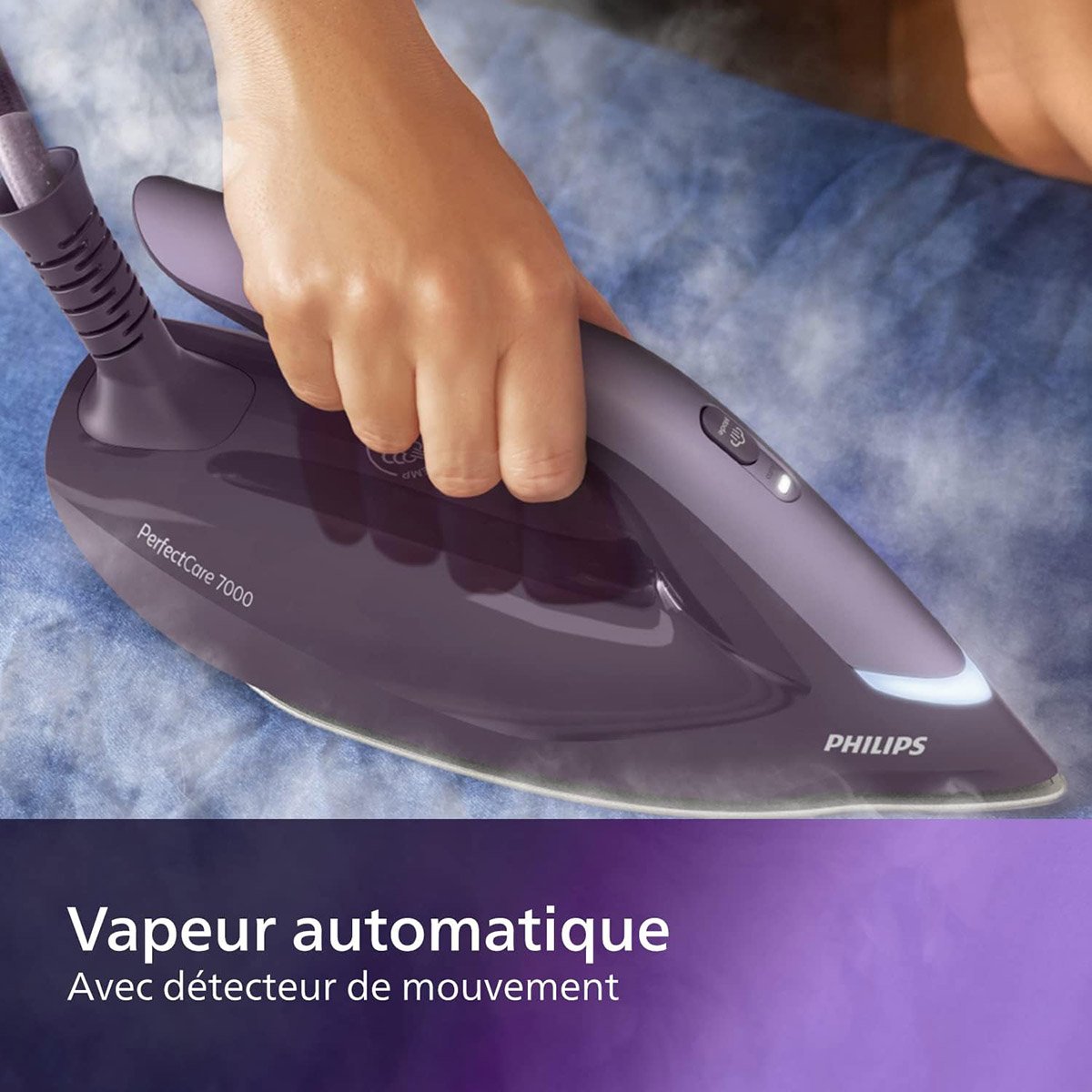 Repassage à la main d'un tissu bleu avec le fer à vapeur PHILIPS PSG7150-30 ; le texte indique "Vapeur automatique, Avec détecteur de mouvement.