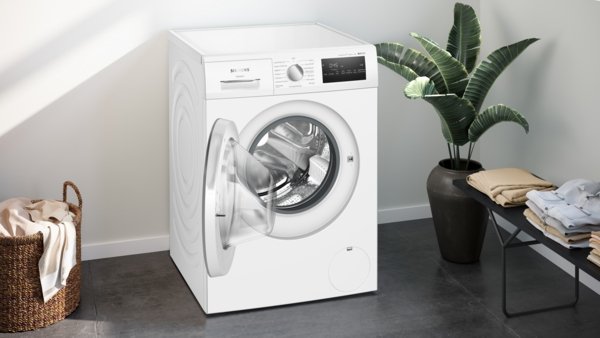 Le SIEMENS WM14N27AFR est un lave-linge blanc à chargement frontal présenté avec sa porte ouverte dans une buanderie moderne.