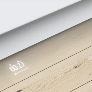 Une horloge numérique affiche 00:27 sur un sol en bois clair, sous des armoires blanches, à côté d'un lave-vaisselle encastrable BOSCH SMV4EB806E.