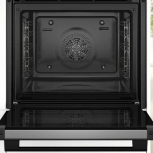 Four BOSCH HBA571BB4 ouvert et vide avec sa porte abaissée, présentant des grilles et un ventilateur à l'intérieur d'une cuisine lumineuse.