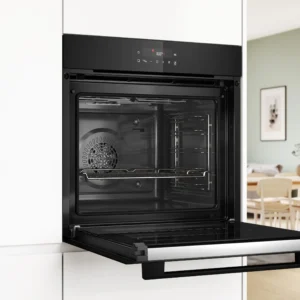Un four encastrable moderne BOSCH HBA571BB4 (Copie) avec la porte ouverte dans une cuisine lumineuse et minimaliste.