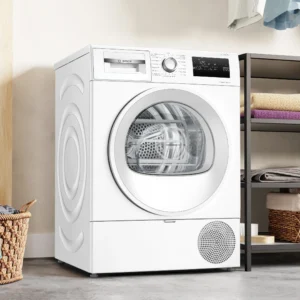 Le lave-linge séchant BOSCH WTH8520MFR blanc moderne est placé à côté d'étagères contenant des serviettes pliées et d'un panier à linge en osier posé sur le sol.