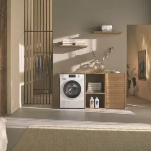 Buanderie moderne équipée d'un lave-linge MIELE WWB360WCS, d'étagères en bois, d'un meuble de rangement et d'un éclairage naturel doux.