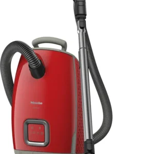 Le Miele GUARD L1 RED PULSE est un aspirateur-traîneau rouge avec un tuyau noir et un accessoire pour le sol. Il se tient debout et est doté de la technologie GUARD L1.