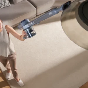 Une femme utilise l'aspirateur sans fil NARWAL pour nettoyer un plafonnier dans son salon.