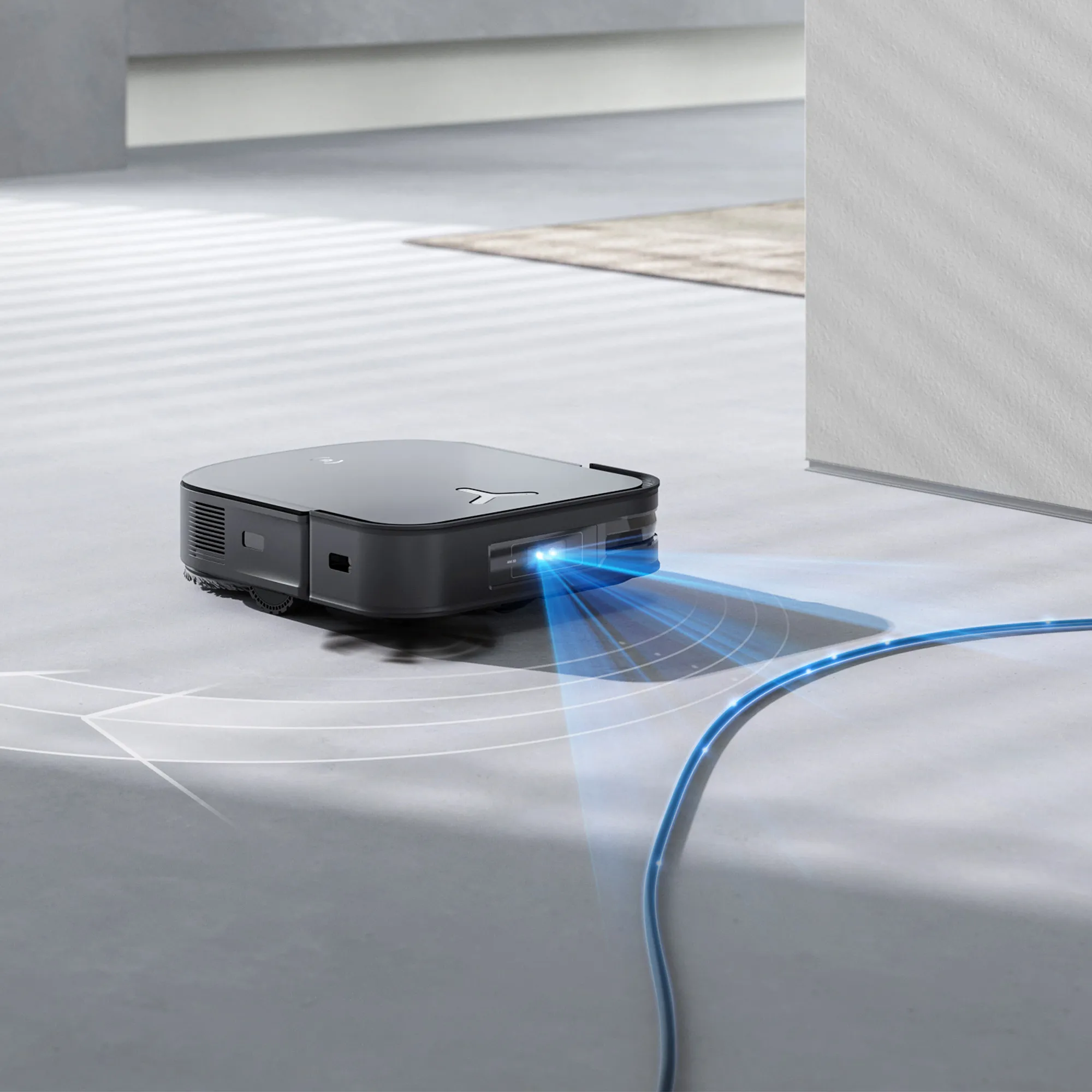 L'ECOVACS X2 COMBO, en noir, utilise des capteurs avancés pour détecter et éviter un câble bleu sur un sol clair.