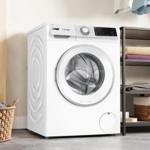 Un lave-linge BOSCH WGG254FAFR (Copie) se trouve à côté d'étagères avec des serviettes soigneusement empilées et un panier à linge au sol.