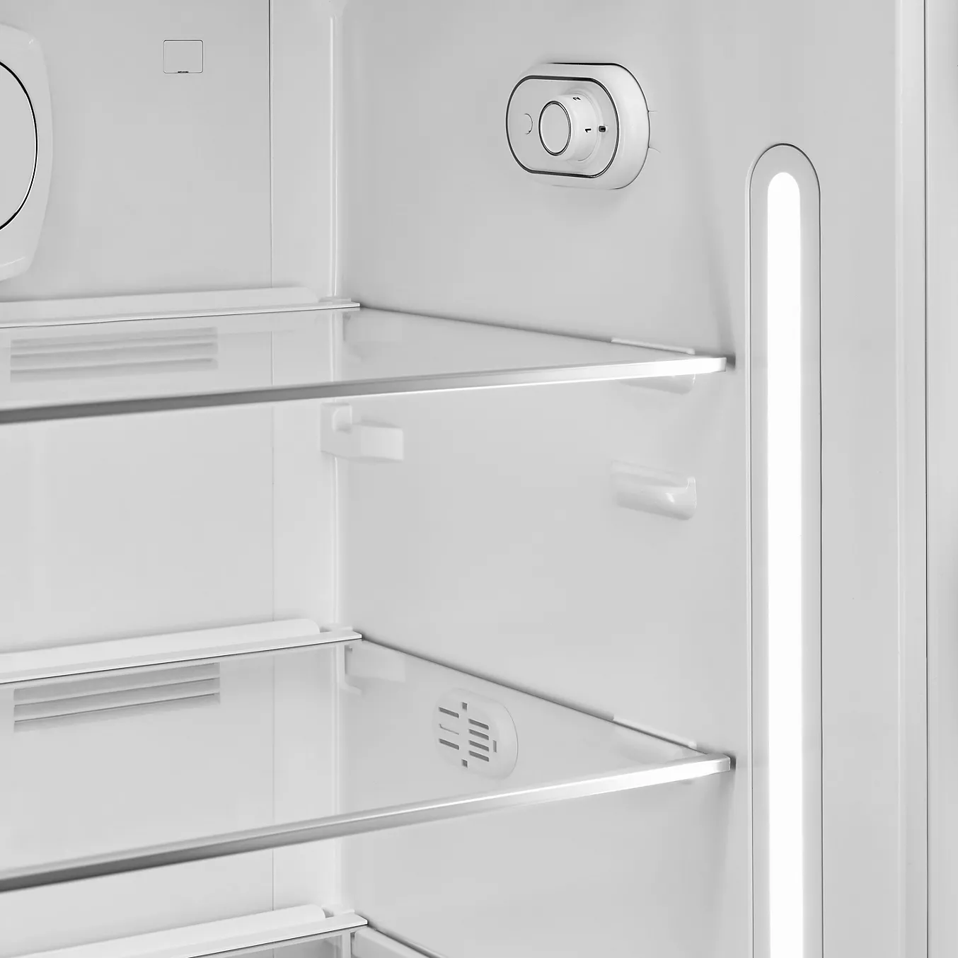 Le réfrigérateur SMEG FAB28RSBM6 dispose d'un intérieur spacieux avec des étagères en verre, un bouton de thermostat et un éclairage LED vertical sur le côté droit.
