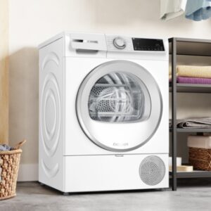 Le lave-linge BOSCH WQJ, un lave-linge blanc moderne, est placé à côté d'étagères remplies de serviettes et d'un panier à linge en osier.