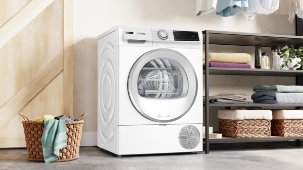 Le lave-linge BOSCH WQJ, un lave-linge blanc moderne, est placé à côté d'étagères remplies de serviettes et d'un panier à linge en osier.