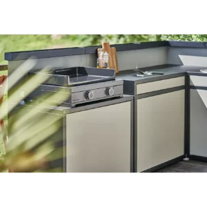 Cuisine extérieure moderne comprenant un gril en acier inoxydable, une plancha FORGE ADOUR MODERN E60 AN, des armoires élégantes et un comptoir avec des planches à découper et des condiments.