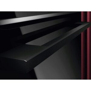 Une élégante étagère noire est posée près d'un sèche-linge AEG TX7PB631SB, placé contre un mur brillant, avec un rideau rouge partiellement visible à droite.