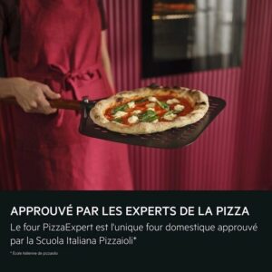 Dans une cuisine moderne, une personne vêtue d'un tablier rouge tient une pizza fraîchement cuite sur une plaque, tandis que le sèche-linge élégant AEG TX7PB631SB est visible à l'arrière-plan.
