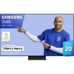 Un homme en chemise bleue montre un téléviseur Samsung affichant le modèle SAMSUNG TQ55S95F, avec des logos visibles et le texte "Thierry Henry" sur l'écran.