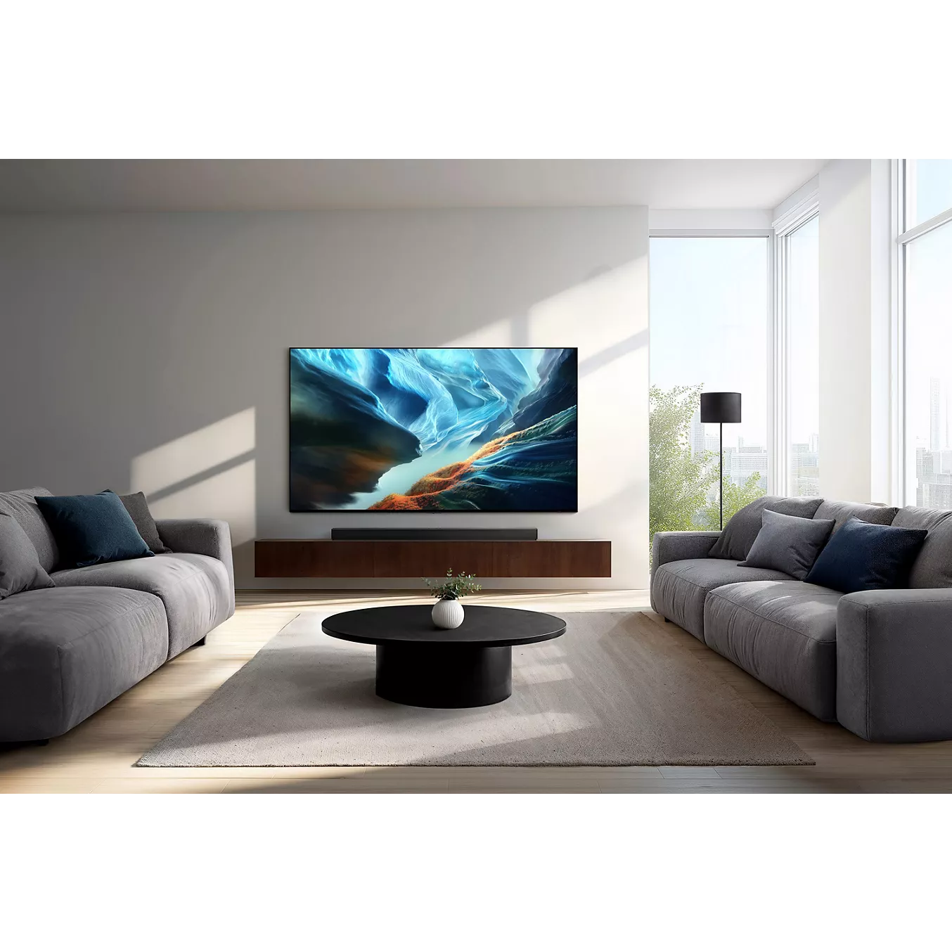 Salon moderne comprenant deux canapés gris, une table basse ronde et un téléviseur mural SAMSUNG TQ65S92H affichant un écran lumineux.