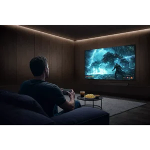 Une personne jouant à un jeu vidéo sur le téléviseur SAMSUNG TQ77S92H dans un salon moderne et sombre avec des snacks sur la table.