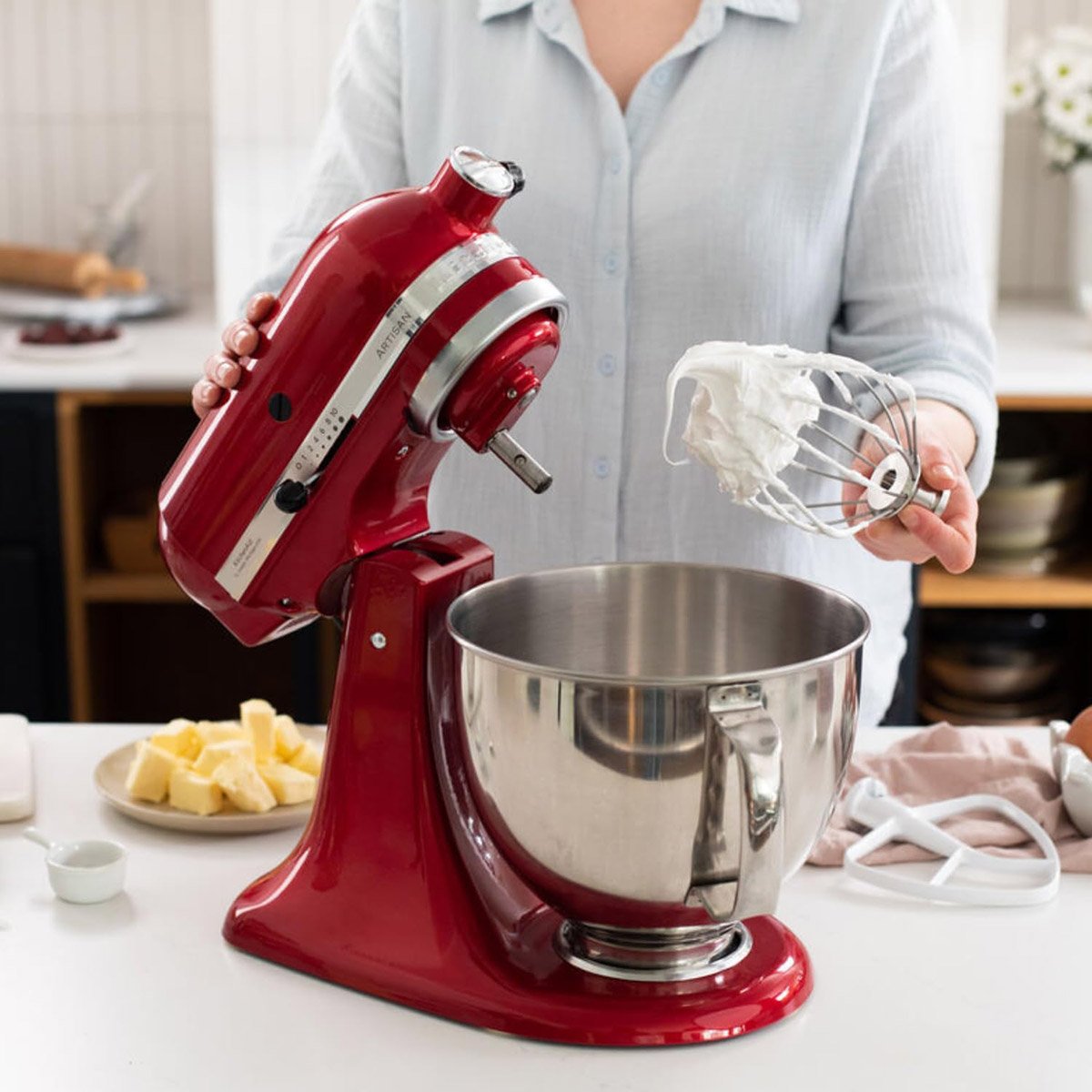 Dans la cuisine, quelqu'un utilise le robot pâtissier KITCHENAID 5KSM175PSEFL et tient son fouet rempli de crème fraîchement fouettée.